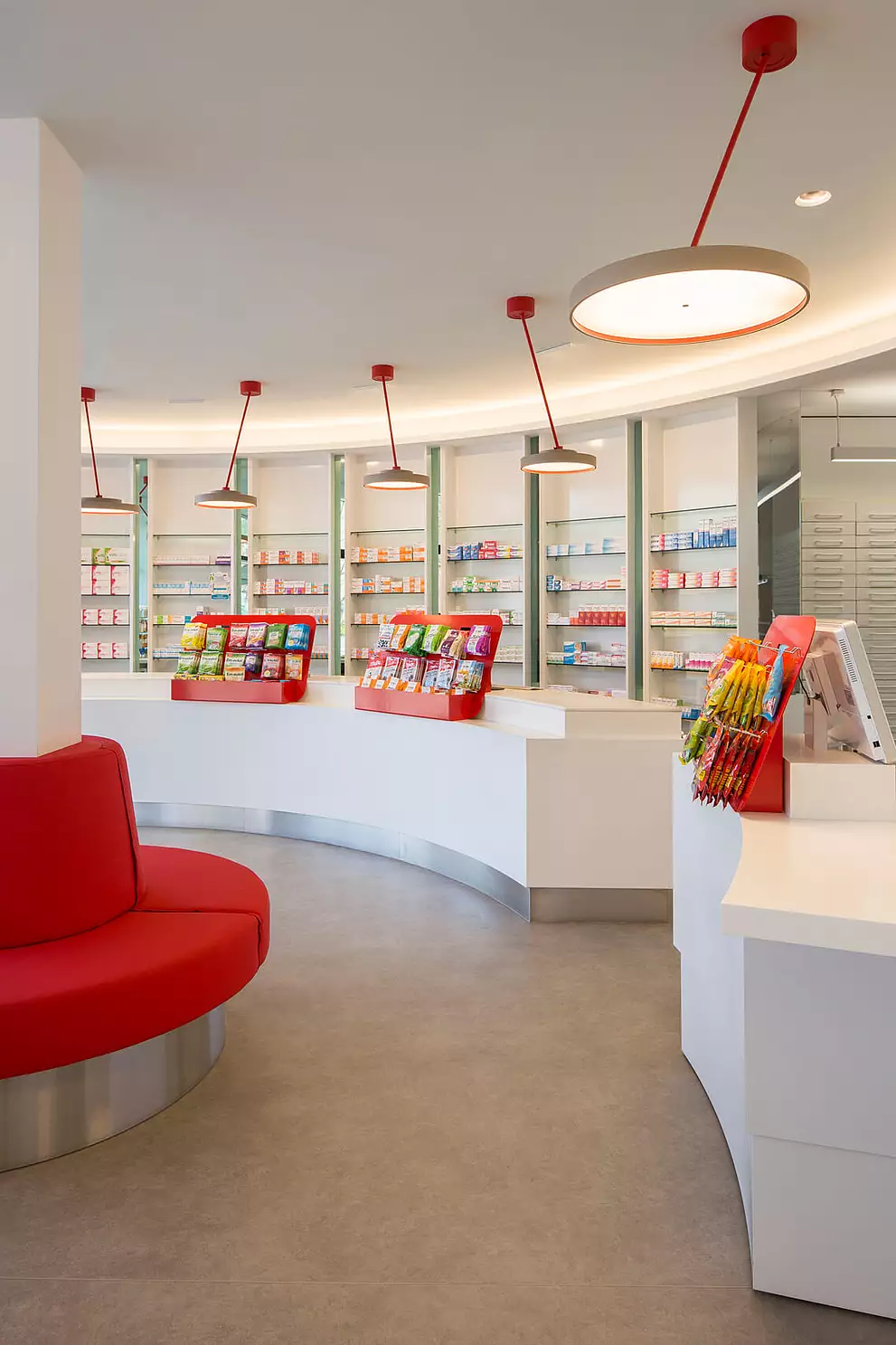 Apothekenverkaufsraum mit Handverkaufstischen und Sichtwahlregale mit Farbakzenten.