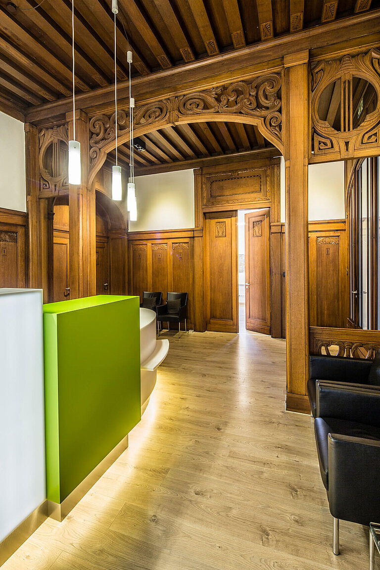 Orthopädiepraxis, holzgetäfelter Raum (ehemals ELBA-Hallen) mit modernem Empfangstresen.